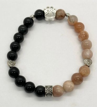 Beaded bracelet with black and beige stones and silver charms.