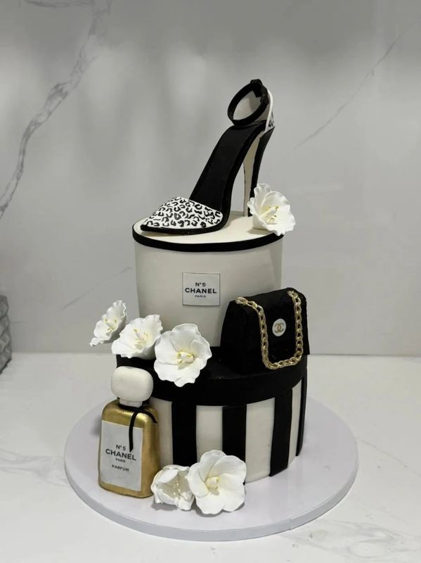 Elegant Chanel-themed cake with a high heel, handbag, and perfume bottle.