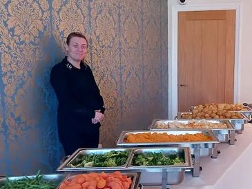 A caterer standing behind a catering table, ready to serve food at an event in Liverpool.