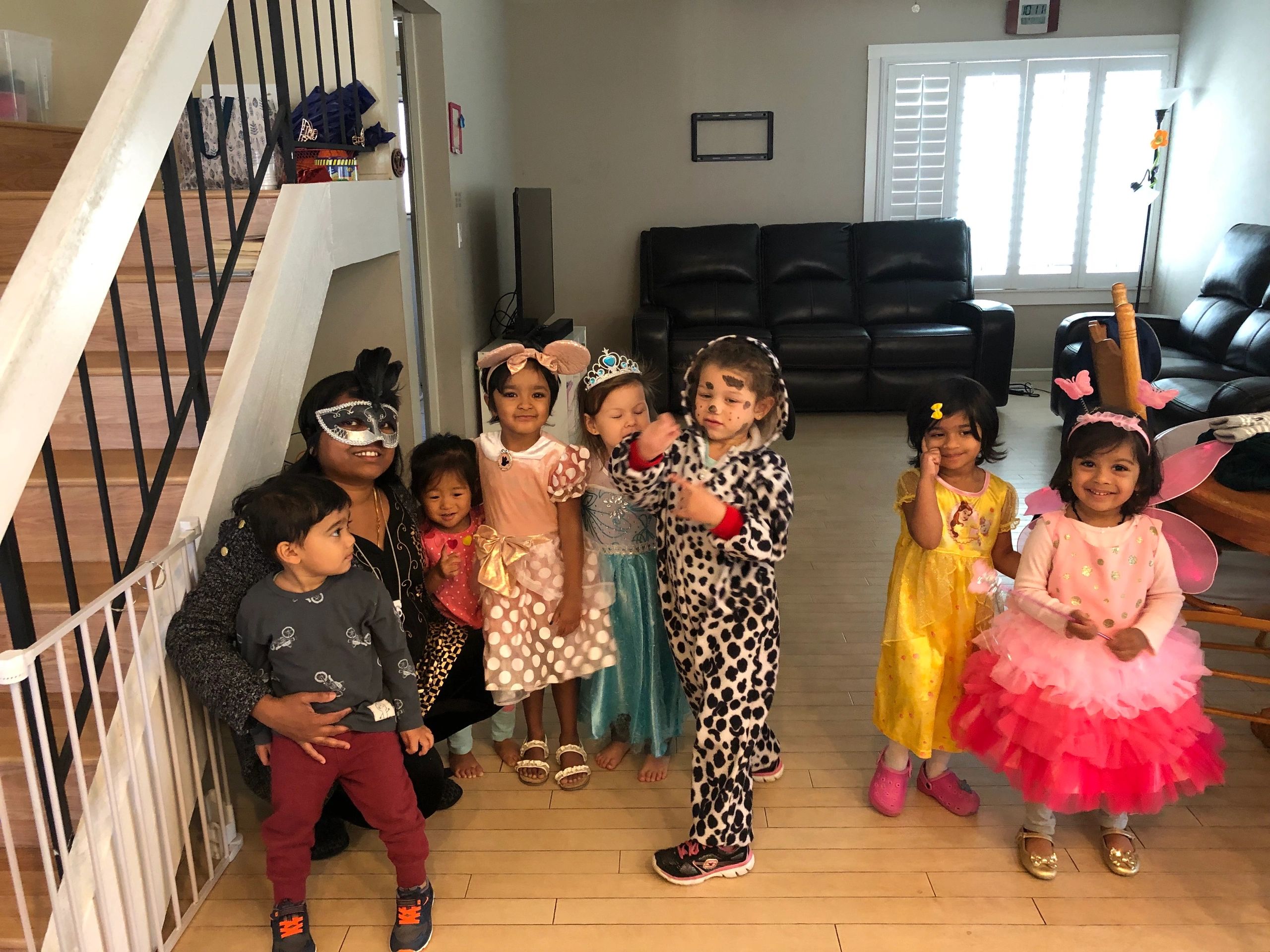 Children and an adult in costumes posing in a living room.