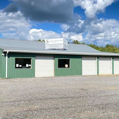 Green commercial building with garage doors and a sign on the roof.