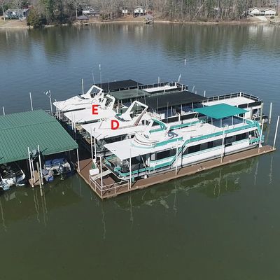 Several boats docked at a marina on a calm lake.