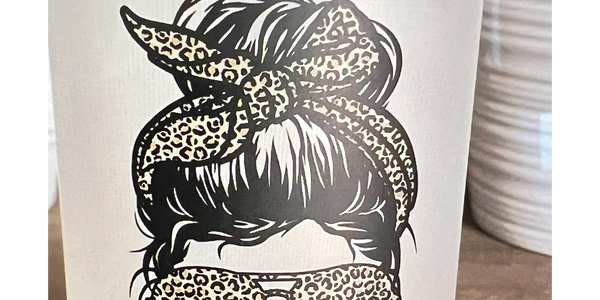 Frosted glass tumbler with a bamboo lid featuring a leopard-print design of a woman’s hair in a messy bun, sunglasses, and headband, with the word “MAMA” in bold leopard-print letters underneath.