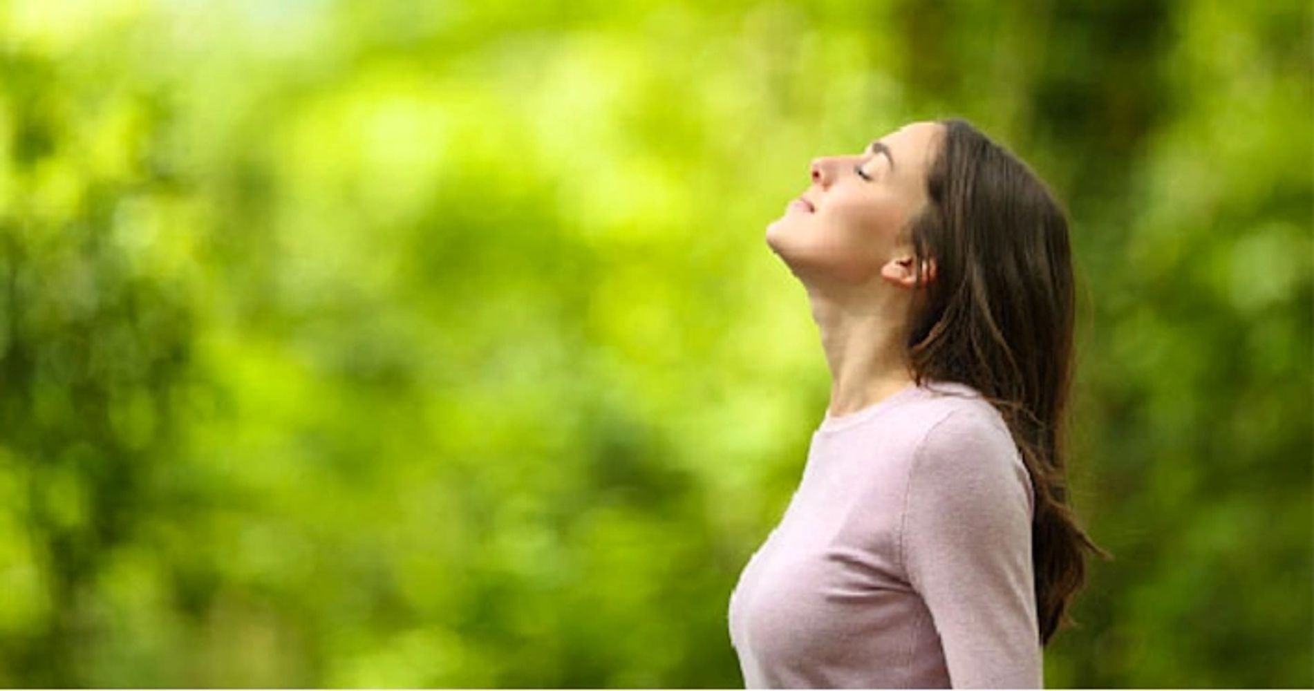 Woman enjoying fresh air in a green outdoor setting.
