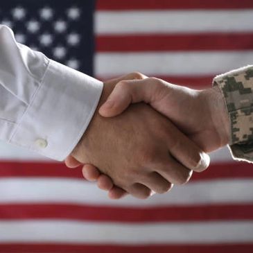 Handshake between a civilian and a soldier with the American flag in the background.