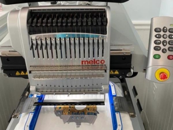 Close-up of a Melco embroidery machine with a control panel.