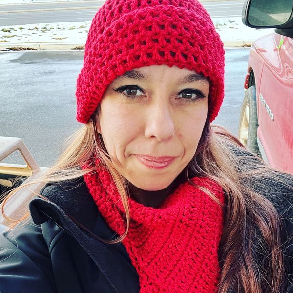 Woman wearing a red knitted hat and scarf outdoors.