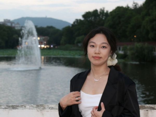 Woman posing by a lake with a fountain.
