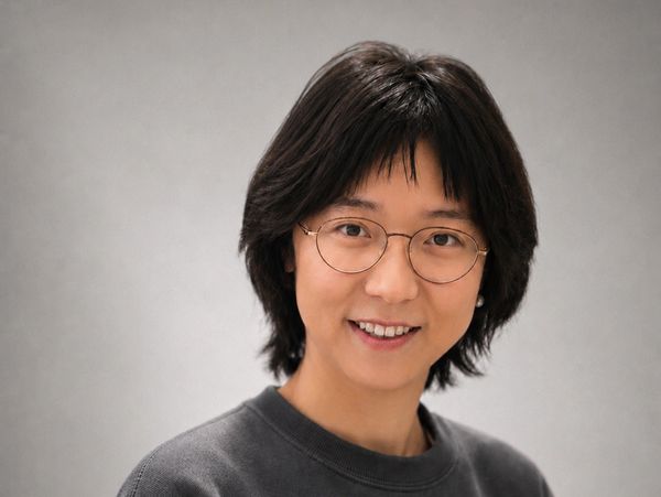 Smiling person with glasses and short hair.