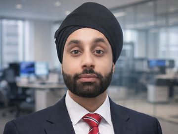 Professional man in a suit and turban in an office setting.