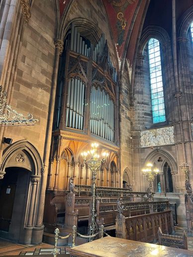 Interior of a historic church with organ pipes and stained glass windows.