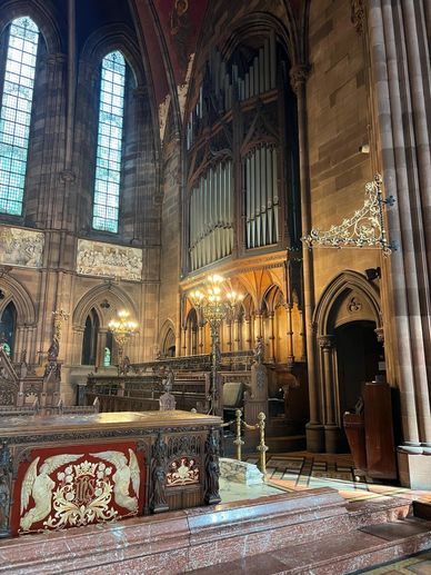 Interior of a grand church with ornate organ and stained glass windows.
