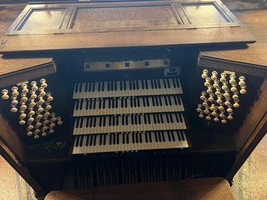 Vintage pipe organ keyboard with multiple manuals and stops.