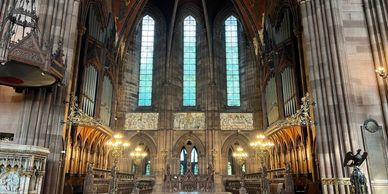 Inside view of a grand cathedral with tall windows and ornate woodwork.