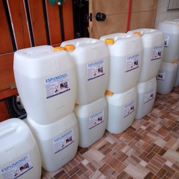 Stacked white containers labeled ESPUMOGEL with yellow caps in a tiled room.