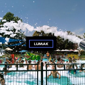 Children enjoying a foam party in a pool on a sunny day.