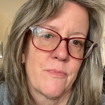 Alison, who is a middle aged white woman, with shoulder length light brown hair, wearing red glasses.