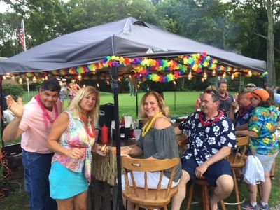 Group enjoying a colorful outdoor party under a decorated canopy.
