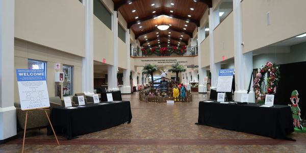 Spacious lobby with welcome signs, black-covered tables, and holiday decorations.