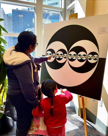 A woman and child interact with a fractal art piece at a gallery.