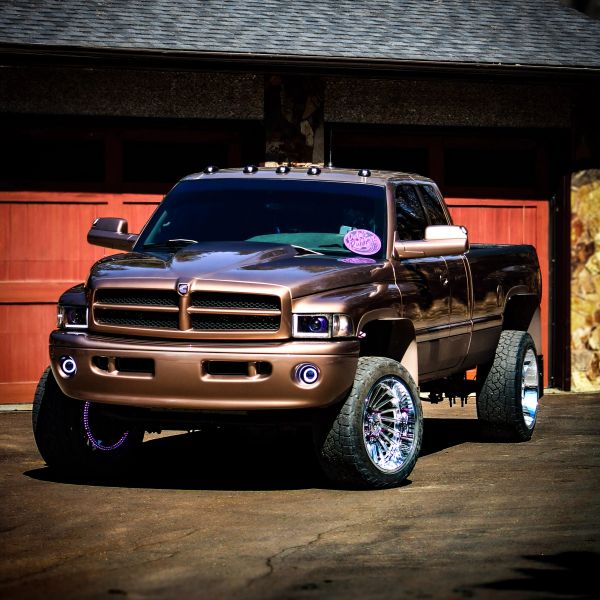 Metallic brown customized Dodge pickup truck with large chrome wheels.