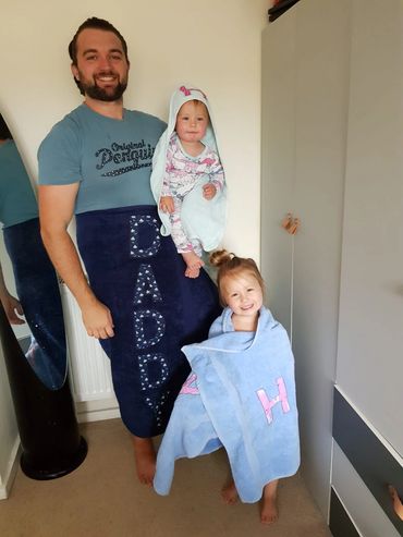 Father and two daughters with personalized towels after bath time.