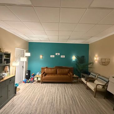 Cozy living room with teal accent wall and brown couch.