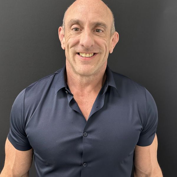 Smiling bald man in a dark shirt against a gray background.