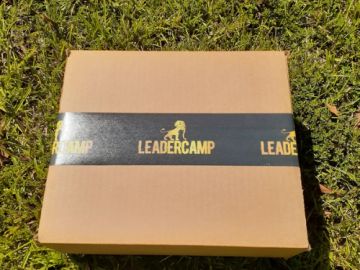A cardboard box with LEADER CAMP tape on grass.