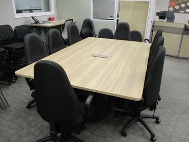 A conference table surrounded by black office chairs in a meeting room.