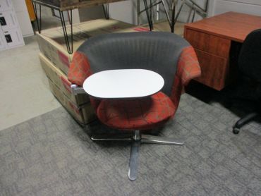 Modern office chair with attached white writing tablet on carpet.