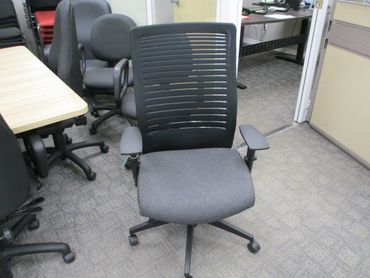 A gray office chair with armrests in a workspace.
