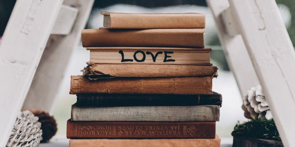 Books stacked under a ladder with the word LOVE written on the pages