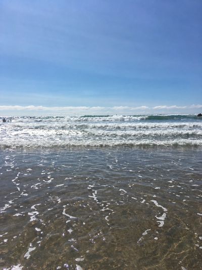Clear ocean waves gently rolling under a bright blue sky.