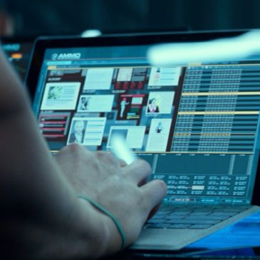 Person working on a laptop with multiple data and charts displayed on screen.