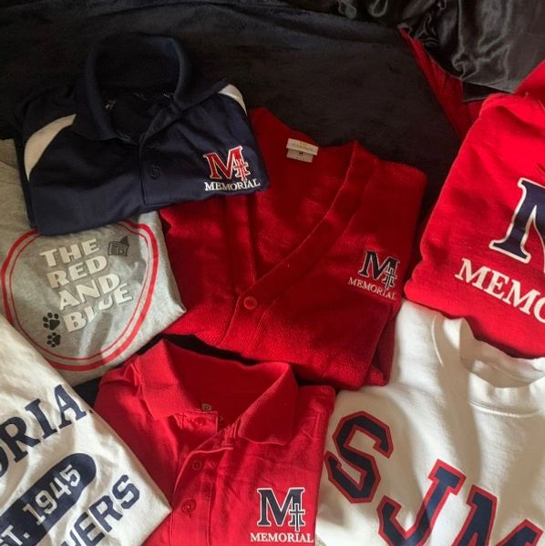 A collection of Memorial school apparel including shirts, sweaters, and sweatshirts in red, white, and blue.