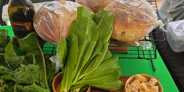 Fresh greens, bread, and olive oil on a table with a green cloth.