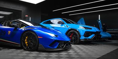 Two blue Lamborghini supercars in a sleek showroom.