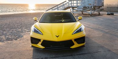 Yellow sports car parked by the beach at sunset.