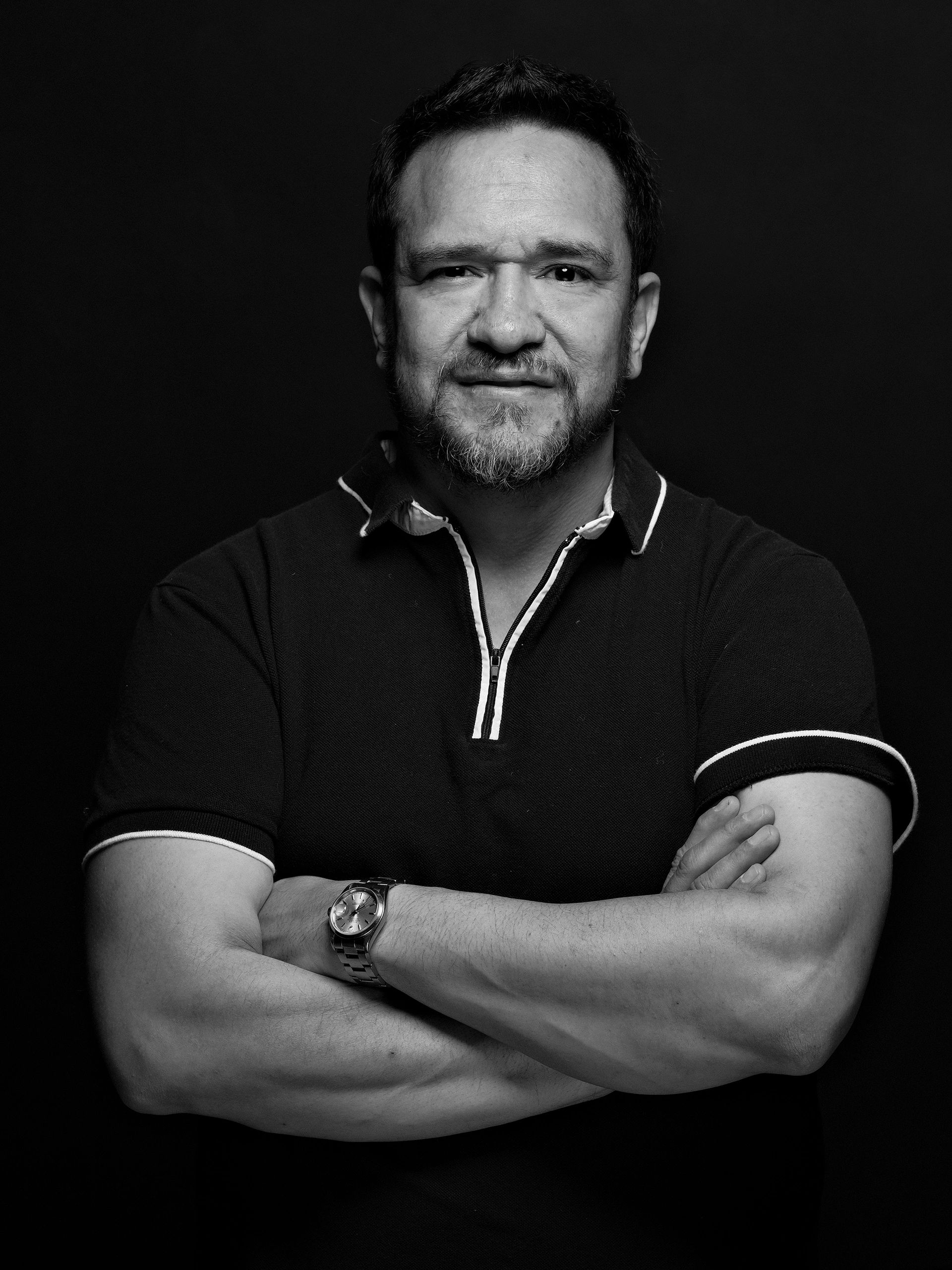 Man with crossed arms looking confident in black and white.