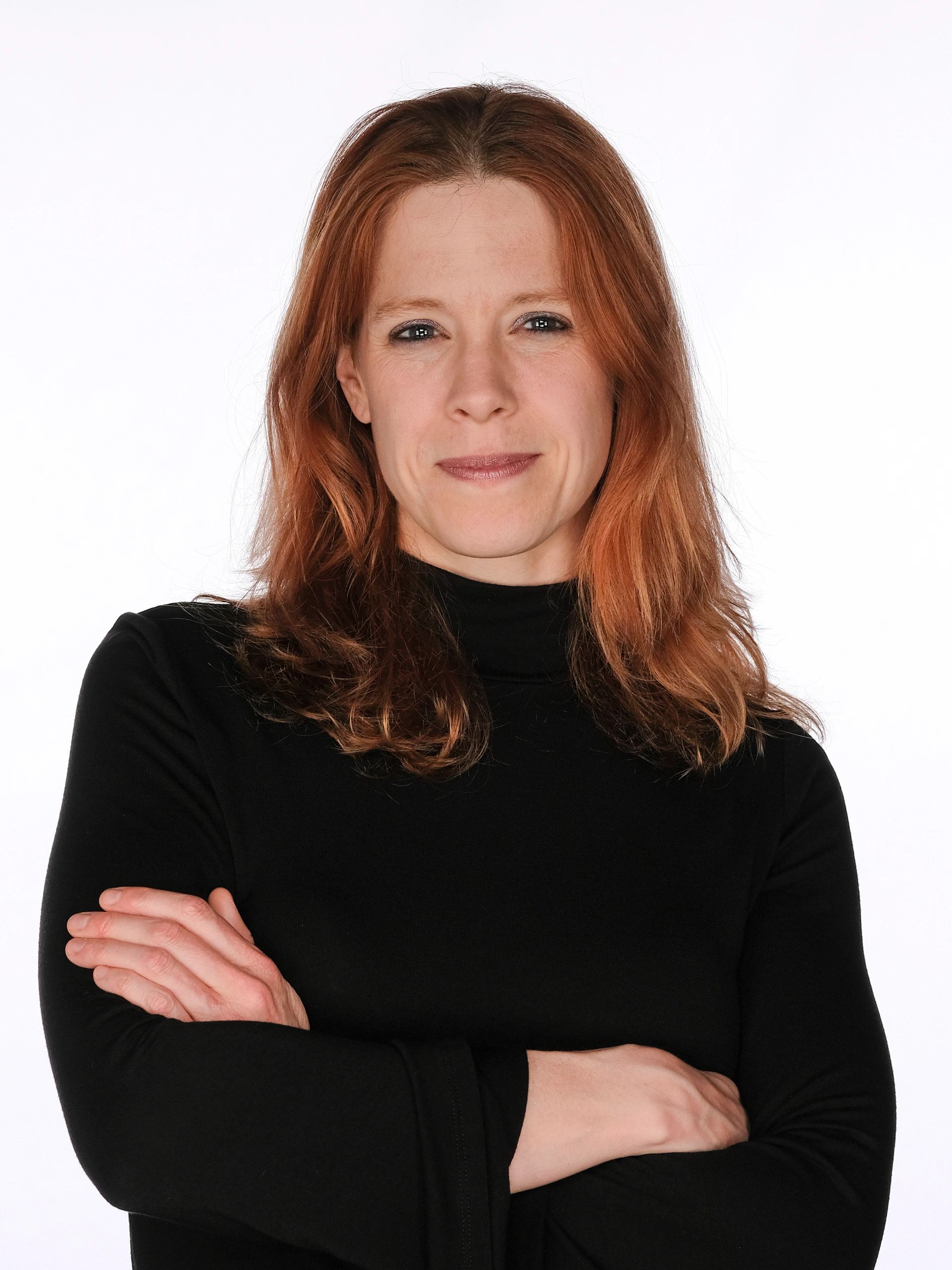 Confident woman with red hair in black turtleneck.