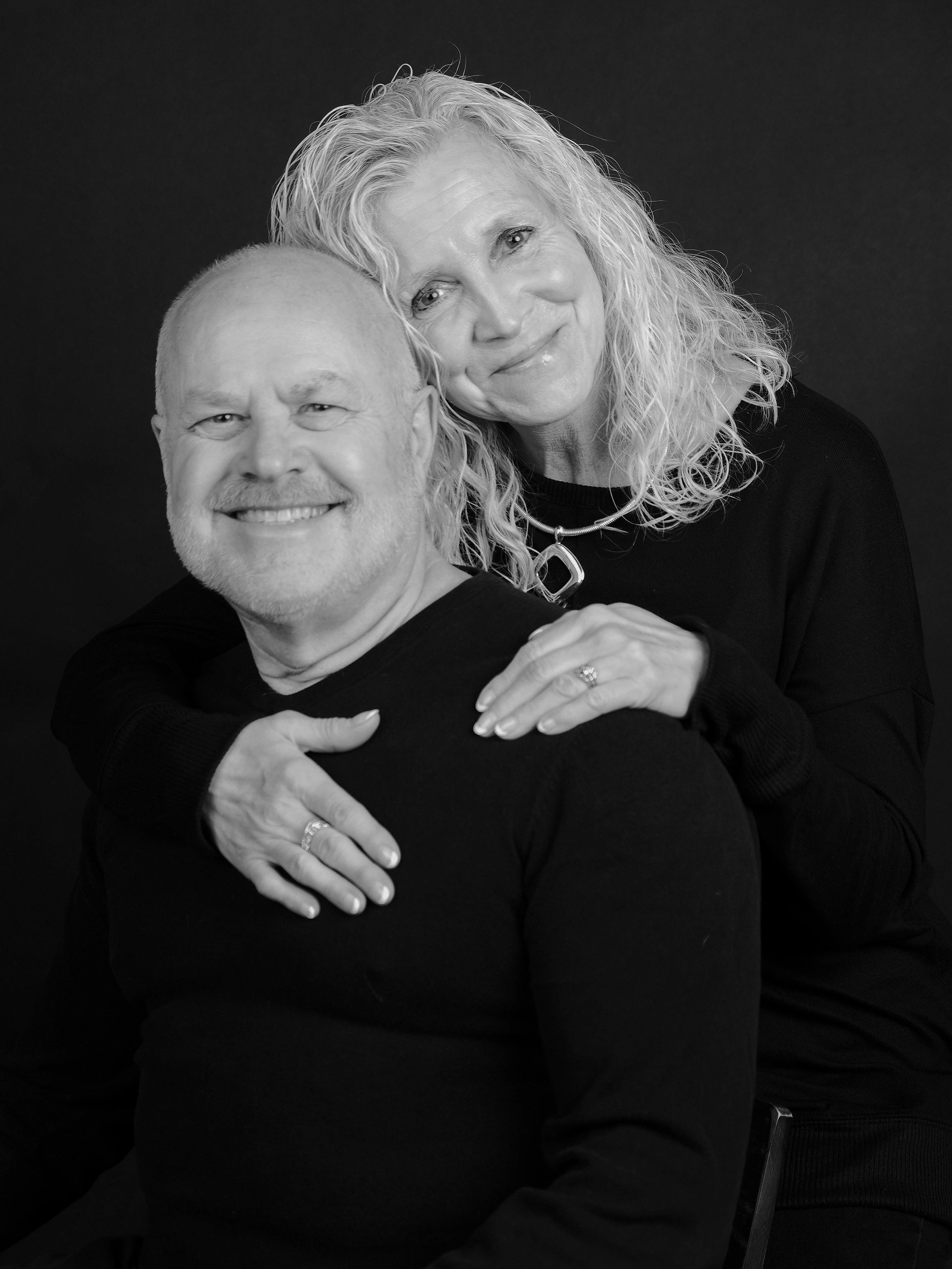 Smiling elderly couple posing together in black and white.