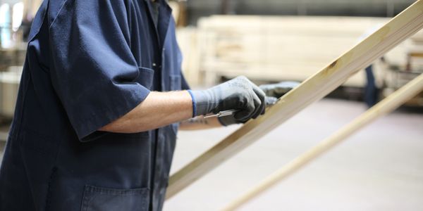 Travailleur inspectant une planche pour cadres de porte et fenêtre à l’usine St-Apollinaire.