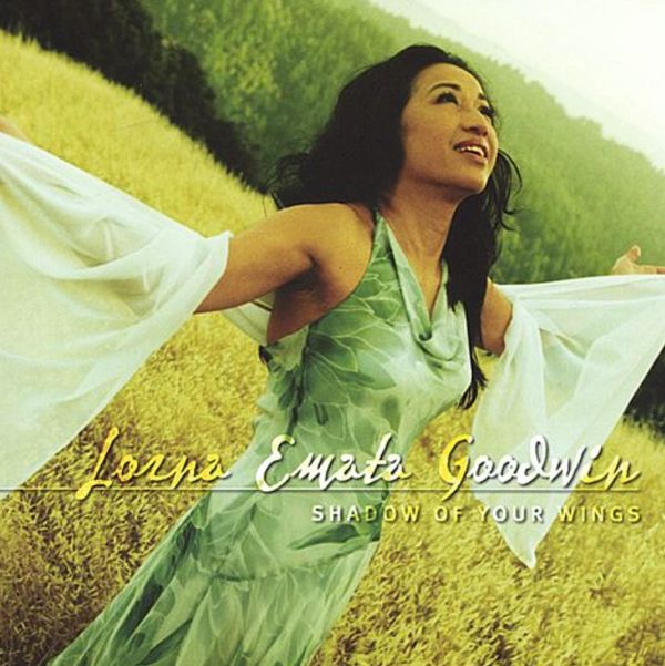 Woman in green dress with arms outstretched in a field.