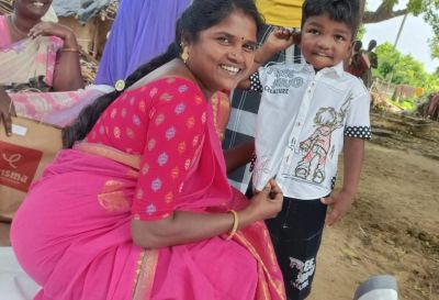Smiling woman in pink saree with a young boy outside.