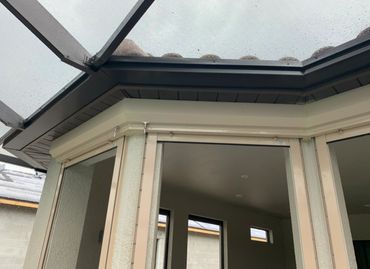 Rain drops on a glass roof over a patio area with windows and beige frames.