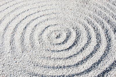 A zen garden with circles expanding out in the sand.