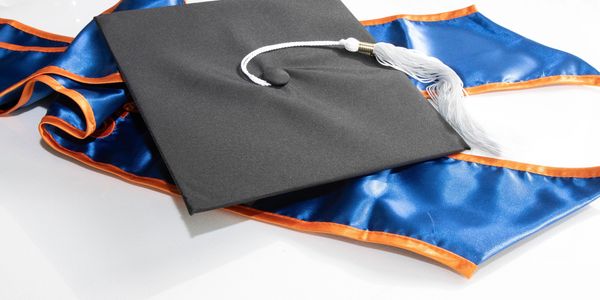 Black graduation cap with white tassel on blue and orange stole.