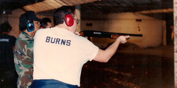 Man shooting at a gun range wearing ear protection.