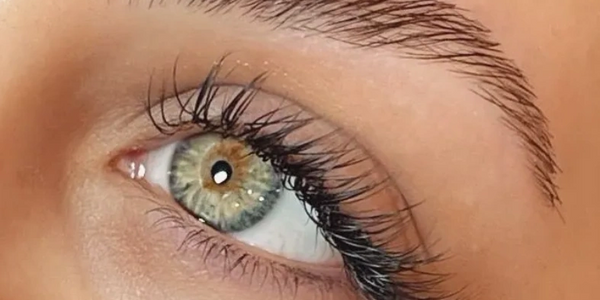 Close-up of an eye with green and brown hues and long eyelashes.